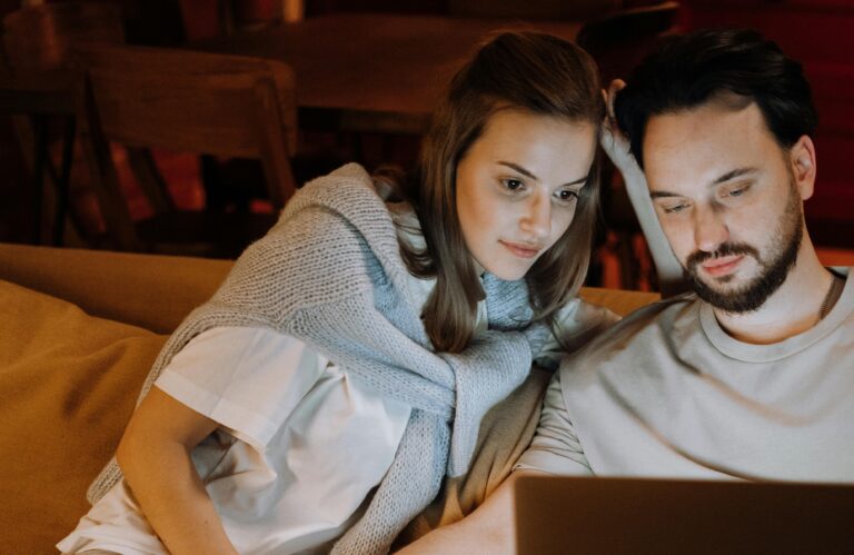 Couple sitting on a couch looking at a laptop